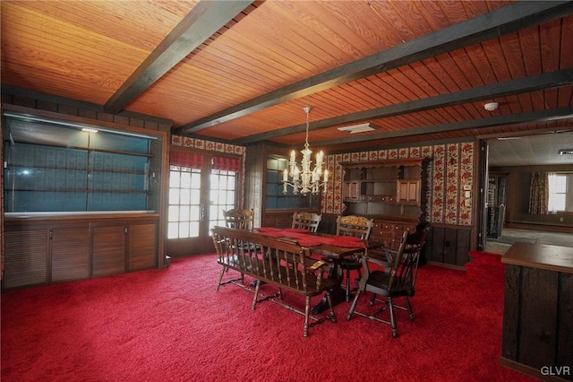 carpeted dining room featuring beam ceiling, a chandelier, a healthy amount of sunlight, and wallpapered walls