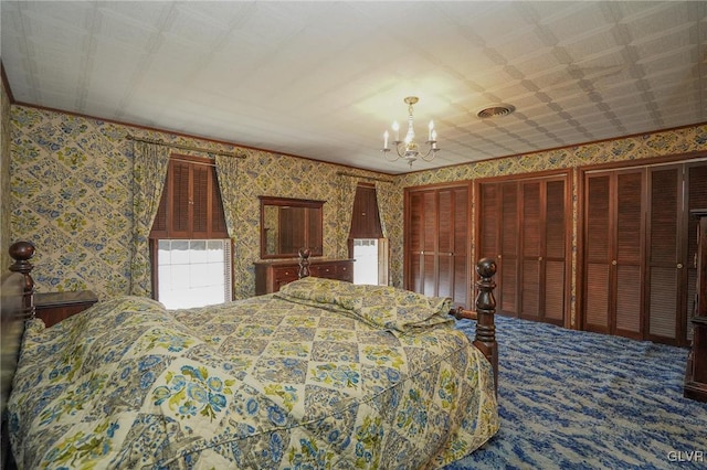 carpeted bedroom featuring two closets, visible vents, a notable chandelier, and wallpapered walls