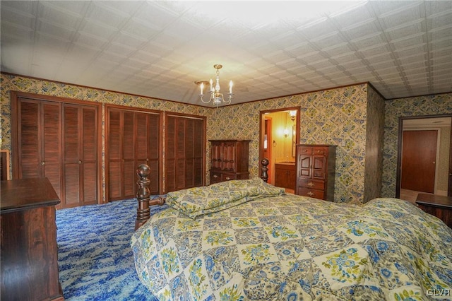 bedroom featuring a notable chandelier, two closets, and wallpapered walls