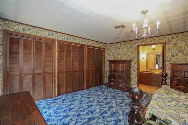 carpeted bedroom featuring wallpapered walls, multiple closets, visible vents, and a chandelier