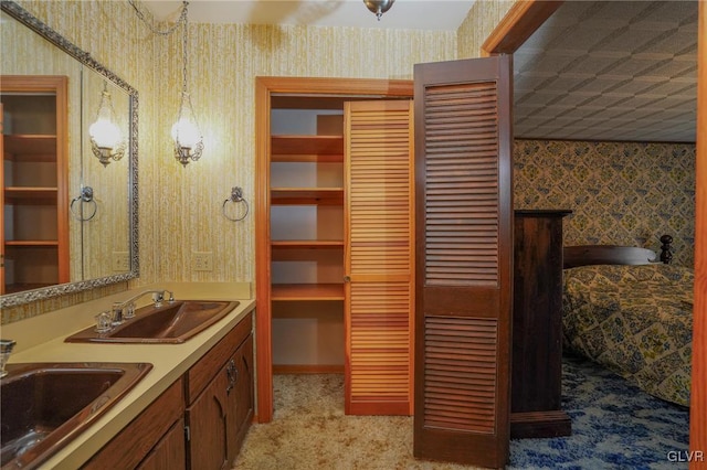 bathroom featuring a sink, a closet, and wallpapered walls