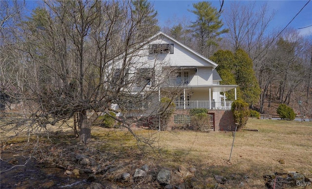 exterior space featuring brick siding, covered porch, and a front lawn