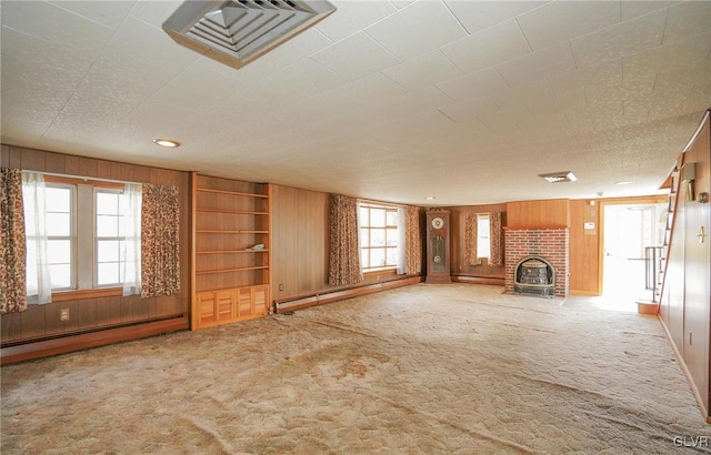 unfurnished living room with visible vents, carpet flooring, and wood walls