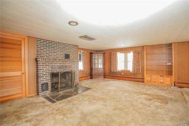 unfurnished living room featuring a baseboard heating unit, a brick fireplace, wooden walls, and carpet