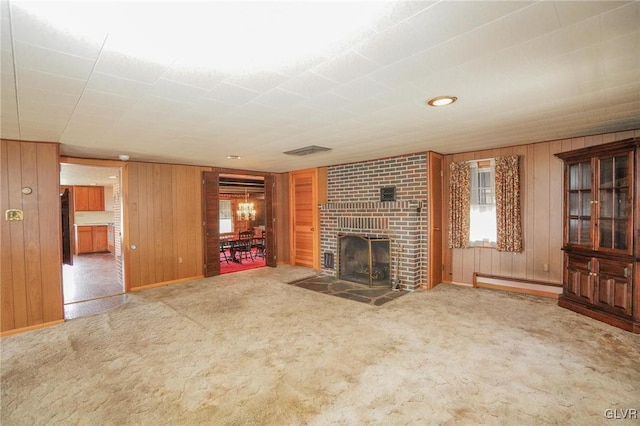 unfurnished living room with wooden walls, a fireplace, carpet, and a baseboard radiator