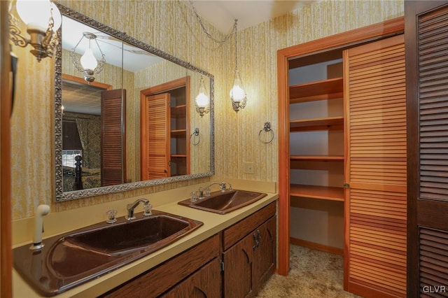 full bath featuring wallpapered walls, a closet, and a sink