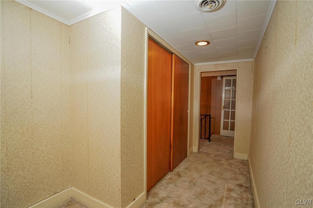 hall featuring ornamental molding, baseboards, visible vents, and light carpet