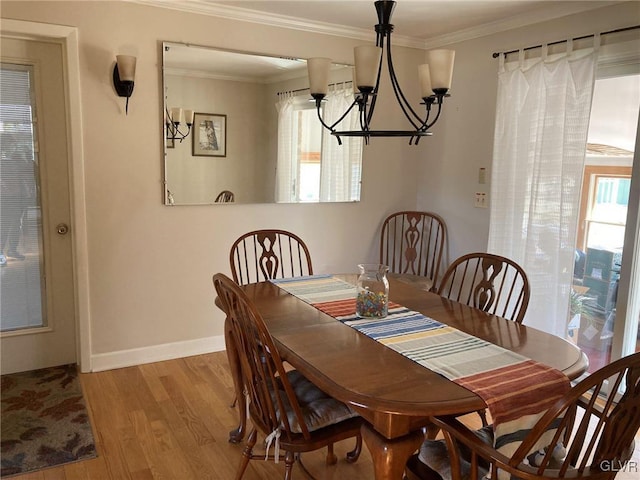 dining room with a notable chandelier, crown molding, baseboards, and wood finished floors