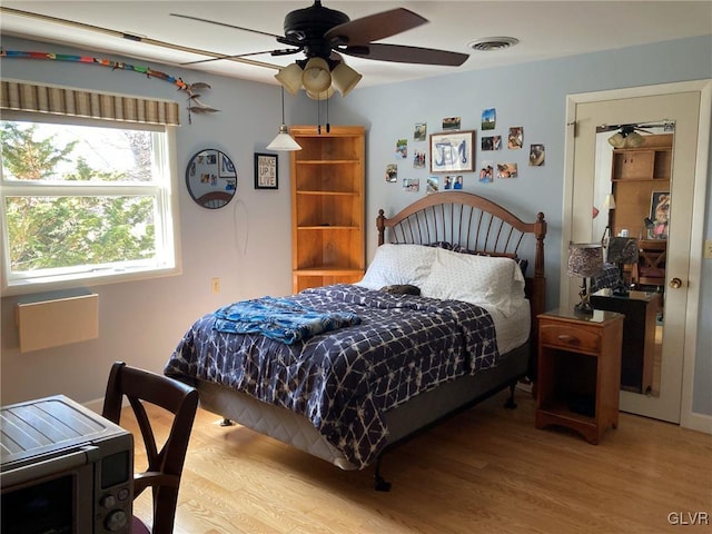 bedroom featuring visible vents, a ceiling fan, and wood finished floors