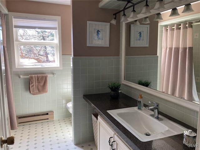 full bathroom featuring a wainscoted wall, toilet, vanity, baseboard heating, and tile walls