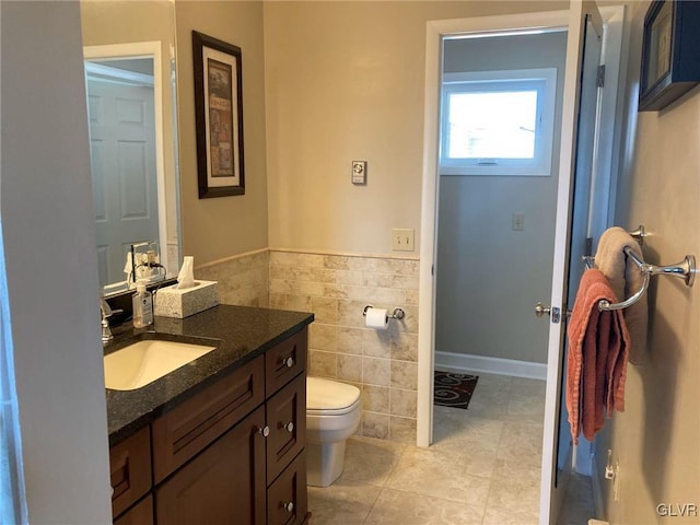 bathroom with vanity, a wainscoted wall, tile walls, toilet, and tile patterned floors