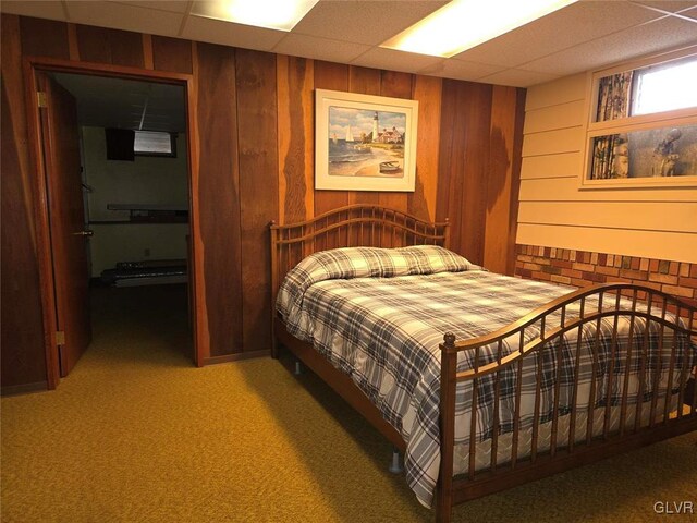 bedroom featuring wooden walls, light colored carpet, and a paneled ceiling