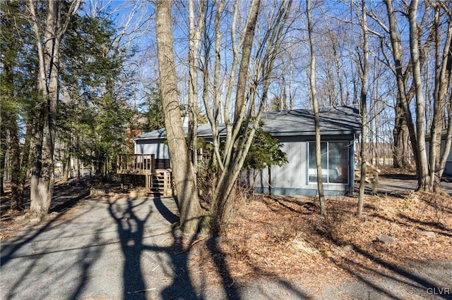 view of side of home featuring a deck, stairs, and a shingled roof