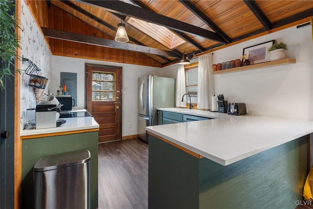 kitchen featuring open shelves, vaulted ceiling with skylight, a peninsula, freestanding refrigerator, and dark wood-style flooring