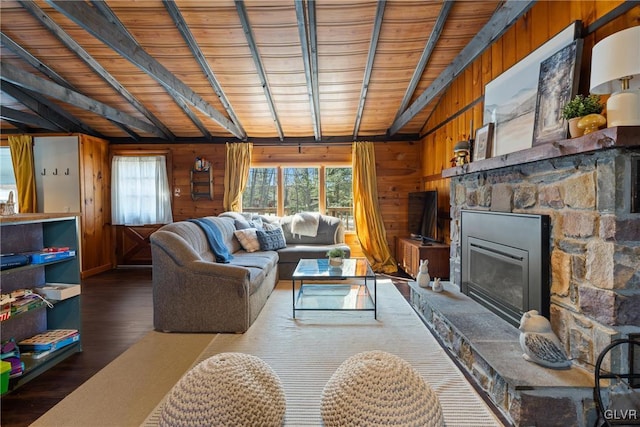 living area with wooden walls, a stone fireplace, and wood finished floors