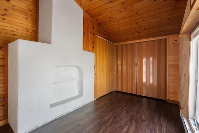 empty room featuring wooden ceiling, wooden walls, dark wood-style flooring, and vaulted ceiling