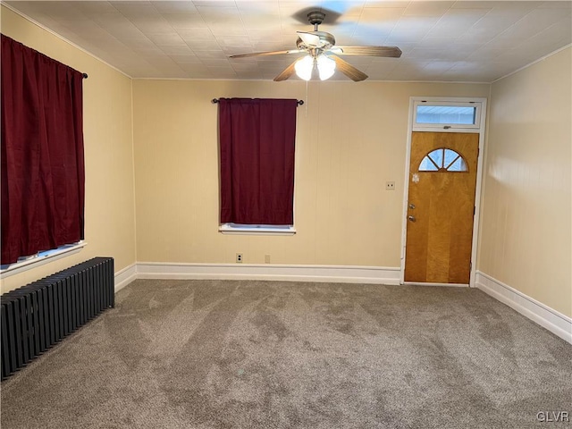 carpeted spare room featuring baseboards, radiator, and ceiling fan