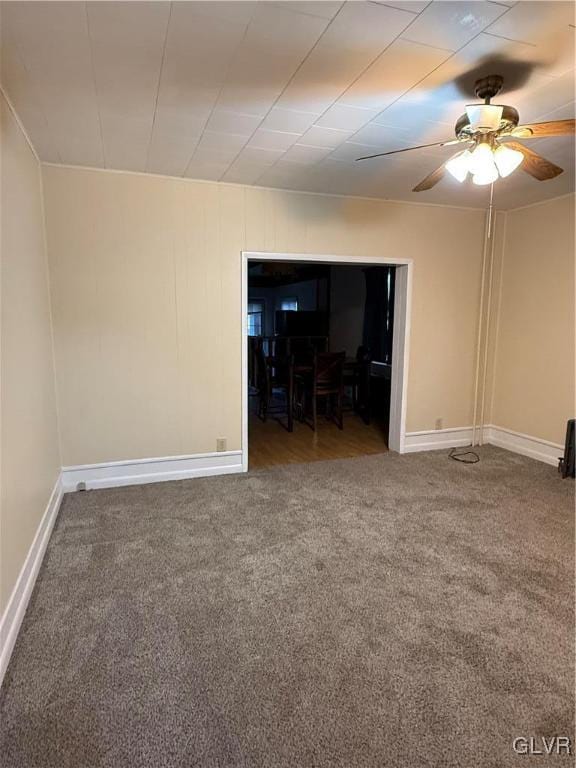 carpeted spare room featuring a ceiling fan and baseboards