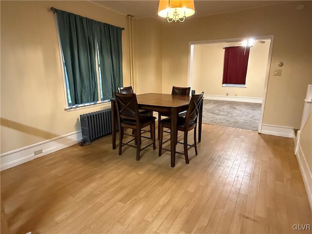 dining space with radiator heating unit, wood finished floors, and baseboards