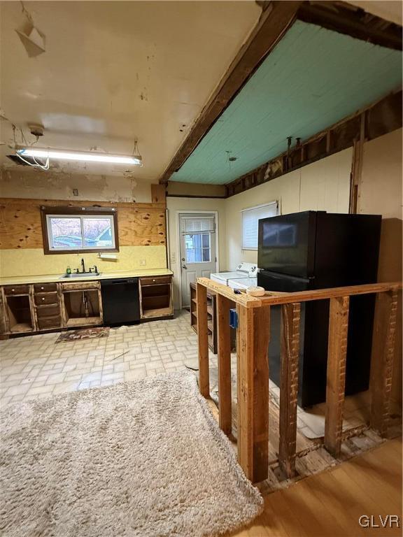 kitchen featuring beamed ceiling, light countertops, and black dishwasher