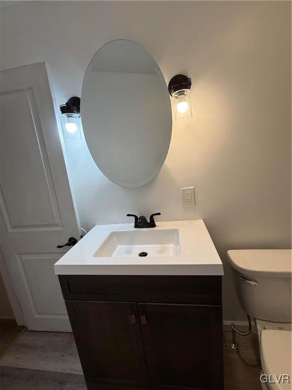 bathroom with toilet, wood finished floors, and vanity