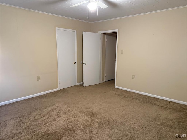 carpeted empty room with ceiling fan, baseboards, and ornamental molding