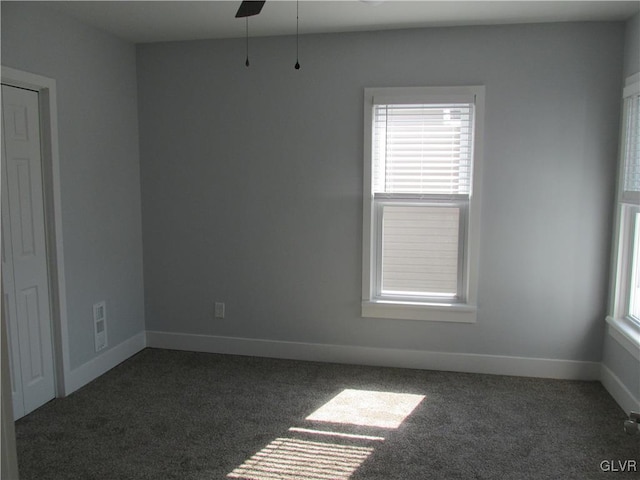 carpeted spare room featuring ceiling fan and baseboards