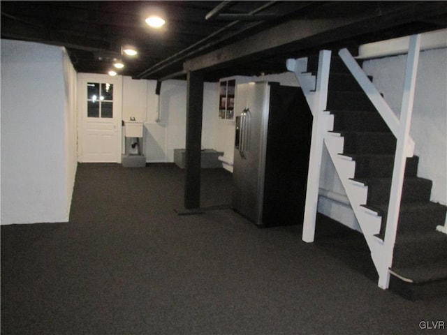 finished below grade area with stairway, stainless steel fridge, and a sink