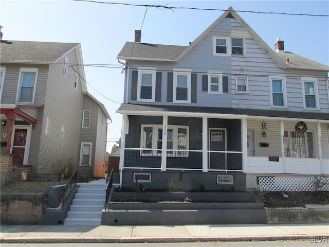 view of front facade with a porch, a chimney, and roof with shingles