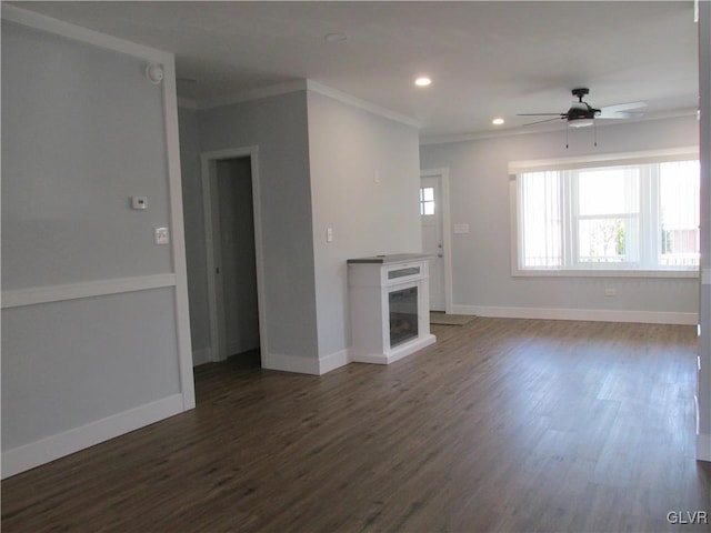 unfurnished living room with dark wood-style floors, baseboards, ornamental molding, and a ceiling fan