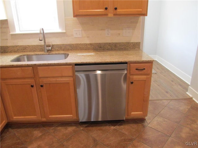 kitchen featuring light stone countertops, dark tile patterned flooring, a sink, dishwasher, and tasteful backsplash