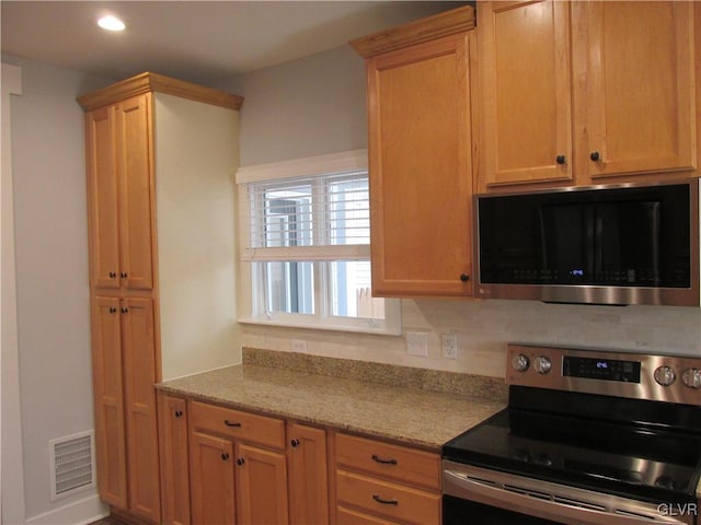 kitchen with recessed lighting, stainless steel appliances, light stone counters, and visible vents