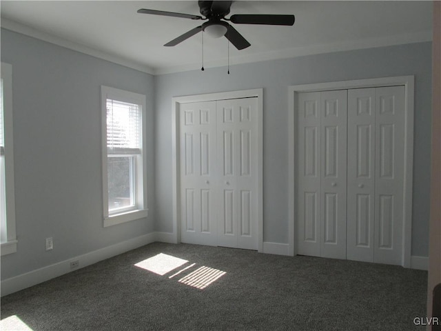 unfurnished bedroom with baseboards, two closets, carpet, and ornamental molding