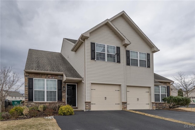 traditional home featuring aphalt driveway, stone siding, an attached garage, and a shingled roof