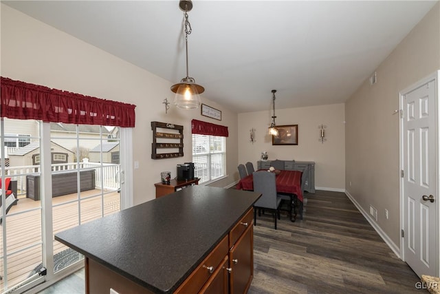 kitchen with dark wood-type flooring, dark countertops, baseboards, and a kitchen island