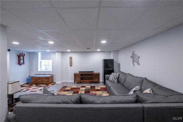 living room featuring a drop ceiling, recessed lighting, baseboards, and wood finished floors