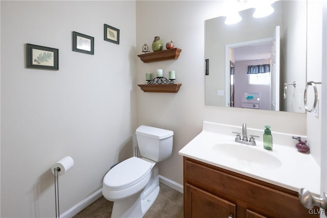 half bathroom featuring baseboards, toilet, and vanity