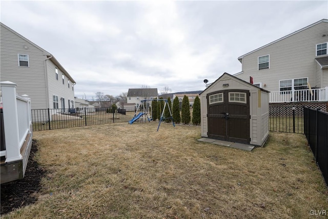 view of yard featuring an outbuilding, a playground, a fenced backyard, and a shed