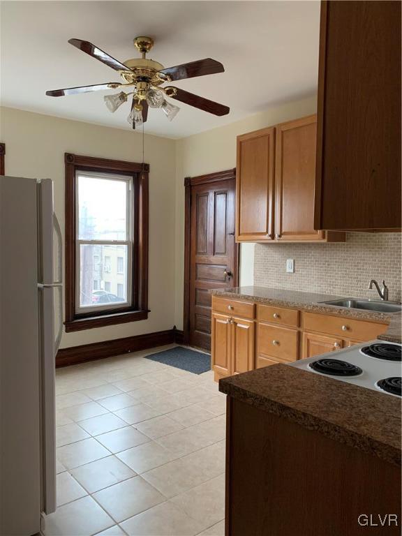 kitchen with a ceiling fan, tasteful backsplash, freestanding refrigerator, and a sink