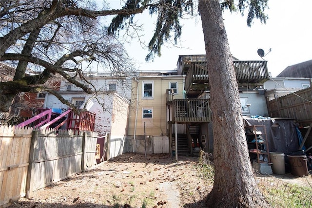 rear view of house featuring stairway, a deck, and fence