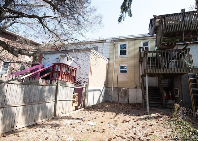 rear view of property featuring a wooden deck, stairs, and fence