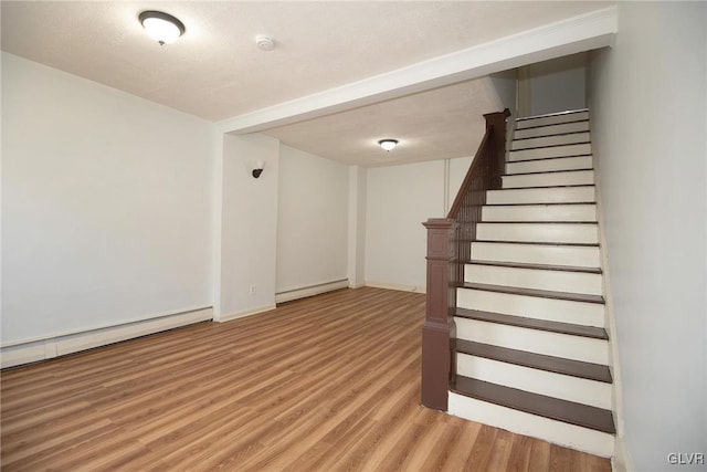 stairway with wood finished floors, baseboards, and a baseboard radiator