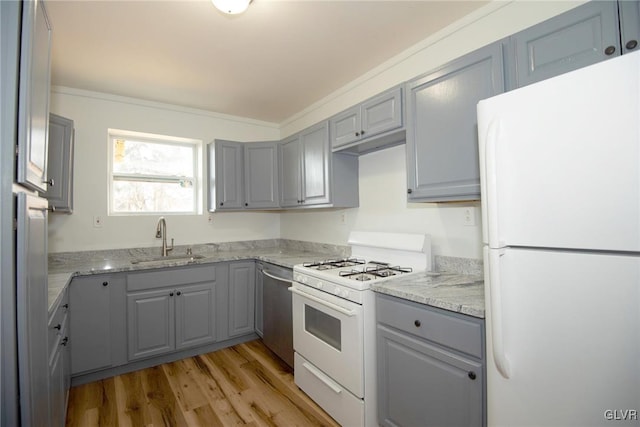 kitchen with white appliances, light stone counters, a sink, gray cabinetry, and light wood-type flooring