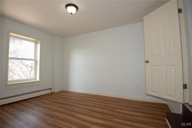 unfurnished room with wood finished floors, baseboards, and a baseboard radiator