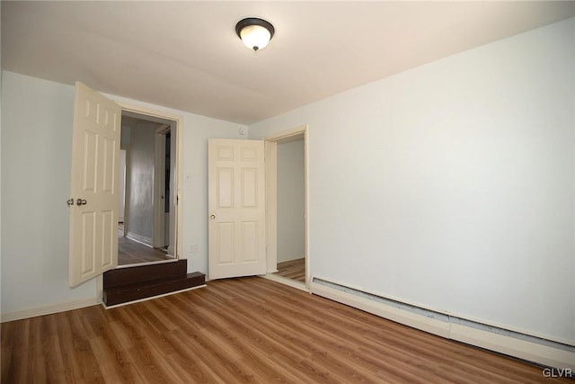 interior space with a baseboard heating unit and wood finished floors