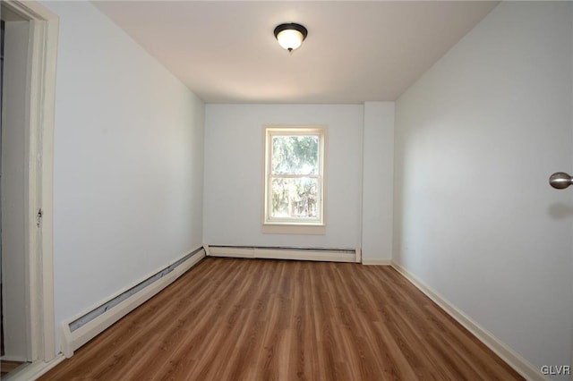 spare room with a baseboard radiator, baseboards, and wood finished floors