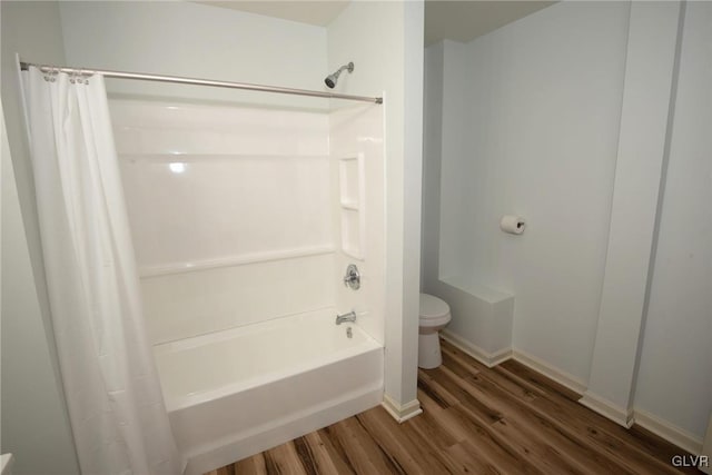 bathroom with shower / tub combo, toilet, wood finished floors, and baseboards