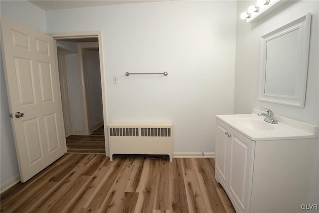 bathroom with vanity, radiator heating unit, baseboards, and wood finished floors