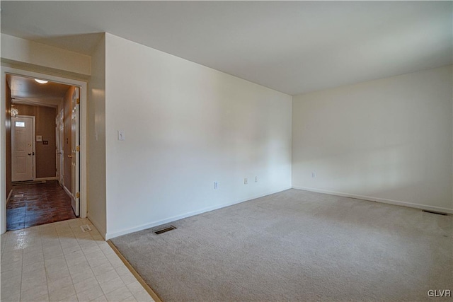 carpeted spare room with visible vents and baseboards