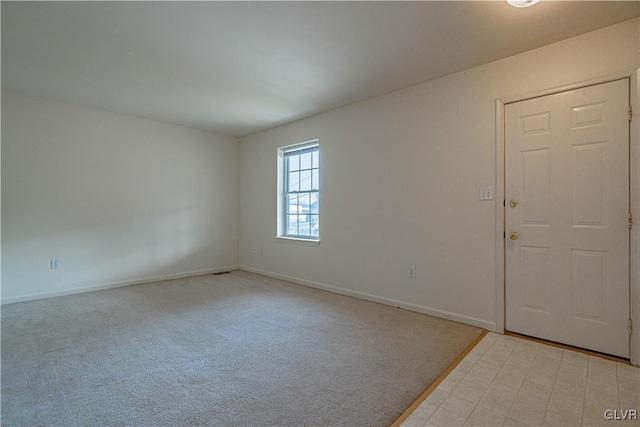 unfurnished room with baseboards and light colored carpet